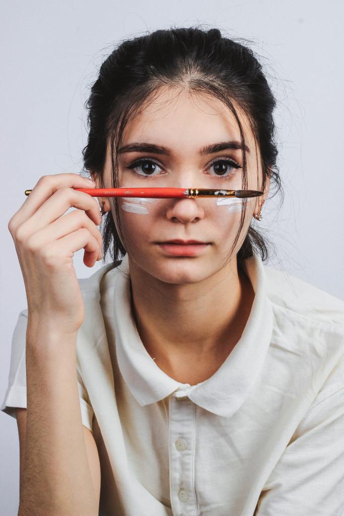 chica con un pincel apoyado en la nariz